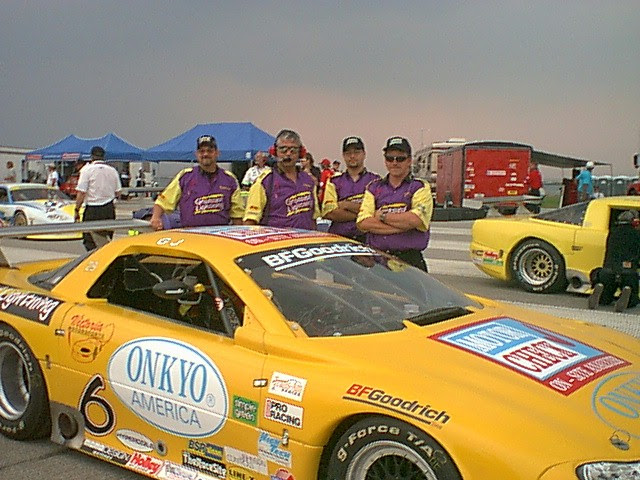 The yellow No. 6 Onkyo America Trans-Am Camaro on the grid with the crew standing behind it